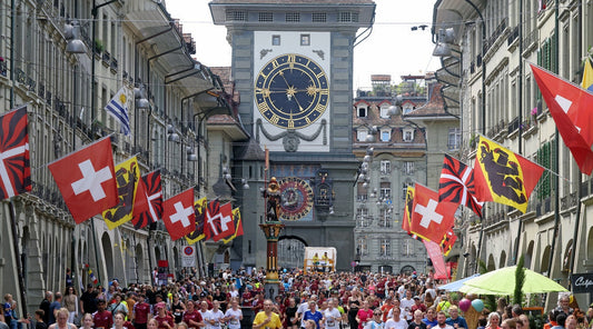 Menschenmenge beim Grand Prix von Bern in der Berner Altstadt: Hunderte Läuferinnen und Läufer rennen durch die mit Schweizer und Berner Fahnen geschmückte Strasse, Zytglogge-Turm im Hingerund